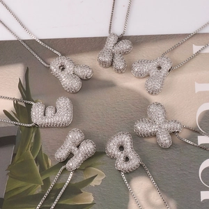 Macro view of bubble letter necklaces with sparkling zircon pavé on a fashion magazine