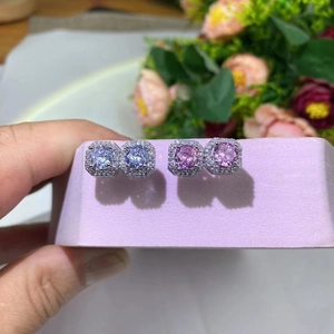 Detailed close-up of square halo stud earrings with pink and blue stones in silver settings
