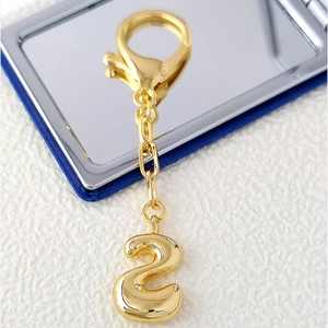 Detailed close-up of 18K gold-plated numeric 2 pendant with high-polish metallic finish