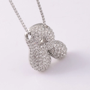 Macro detail of silver-tone box chain and sparkling zircon-paved cartoon pendant necklace