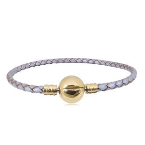 Primer plano de pulsera de cuero trenzado plateado con cierre de esfera dorada