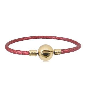 Vista macro de pulsera de cuero trenzado rojo con un cierre esférico dorado brillante