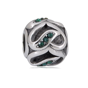 Detailed close-up of a vintage silver charm bead with green zircon and hollow heart patterns