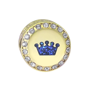 Macro shot of gold-plated crown charm with blue glitter and cubic zirconia crystals