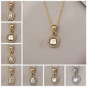 Primo piano di ciondoli di lusso in zircone in varie forme geometriche con catena d'oro