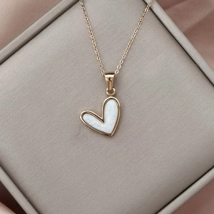Elegante collar con colgante de corazón en oro rosa y nácar blanco sobre fondo de seda