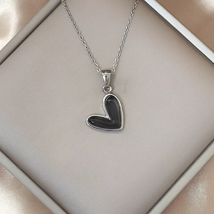 Vista de detalle de collar con colgante de corazón negro en caja con seda suave