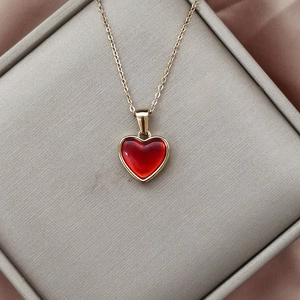 Detailaufnahme eines roten Herzanhängers an einer Goldkette auf einer Schmuckbox