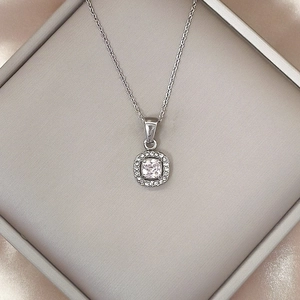 Dettaglio della collana con ciondolo halo d'argento con zircone quadrato su una scatola grigia