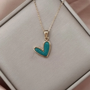 Detalle del colgante de corazón dorado con incrustación de turquesa en caja de lujo