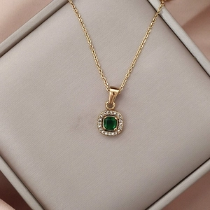 Dettaglio della collana dorata con pendente quadrato verde smeraldo e zirconi lucenti
