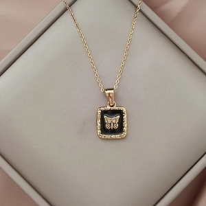 Makroaufnahme Gold-Schmetterling-Anhänger mit schwarzer Emaille auf rosa Seidenstoff