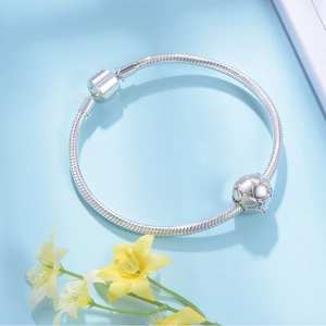 Detail van zilveren slangenarmband met getextureerde bedel en blauwe kristallen accenten
