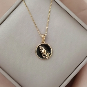 Nahaufnahme der Vintage Goldhalskette mit schwarzem Medaillon und Relief betender Hände