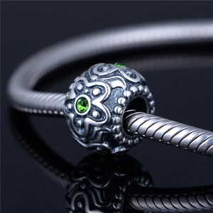 Macro-detail van S925 zilveren bloemkraal met groene stenen aan een slangenketting