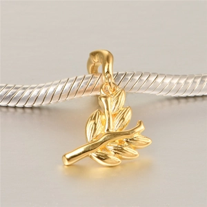Detailed macro view of a polished gold bamboo leaf pendant on a silver snake chain necklace