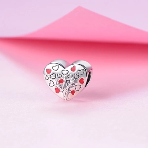 Dettaglio ravvicinato di charm a cuore in argento S925 con albero della vita rosso