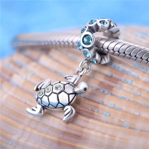 Détail macro du pendentif tortue de mer en argent avec pierres vertes et strass