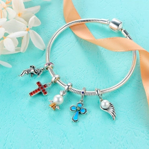 Sterling silver snake chain bracelet with diamond cross and angel charms on blue surface