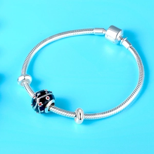 Zilveren slangenarmband met zwarte bloemige emaille bedel en rode strass steentjes