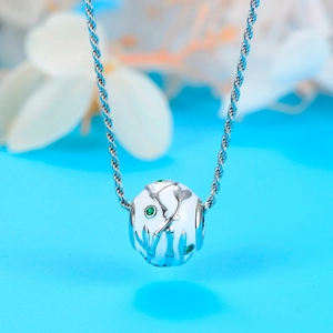 Detail van een 925 zilveren bedel met wit emaille en groene edelstenen op de ketting