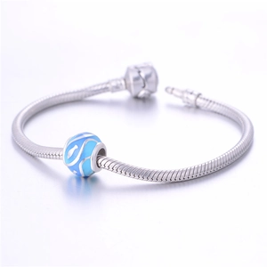 Primer plano de charm de plata S925 con motivos de peces azules en pulsera de serpiente