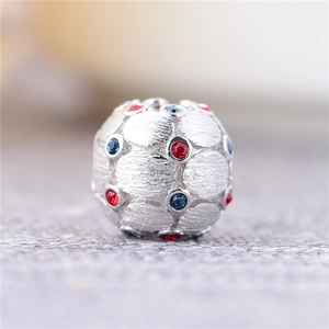 Foto macro de una cuenta de plata esterlina S925 con piedras rojas y azules