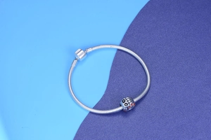 Close-up of Halloween pumpkin charm on silver snake chain bracelet with cylindrical clasp