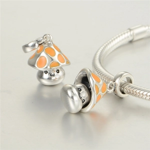 Macro shot of S925 silver mushroom charms with orange enamel and engraved facial details
