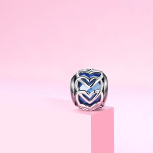 Detalle macro del abalorio de corazón en plata S925 con cristal azul sobre superficie rosa