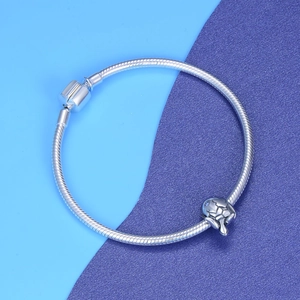 Polished silver sea turtle charm with blue gemstone eye on classic snake chain bracelet