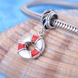 Détail macro du charm bouée de sauvetage en argent S925 et émail rouge sur un bracelet