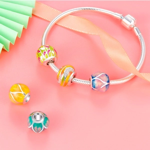 Pulsera de dijes en plata 925 con cuentas de esmalte de colores sobre fondo rosa