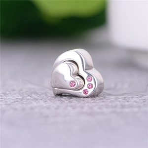 Dettaglio macro del ciondolo a cuore in argento con design a strati e gemme rosa