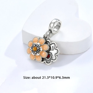 Detalle de charm en plata S925 con flor de esmalte naranja y letra L grabada con corazón