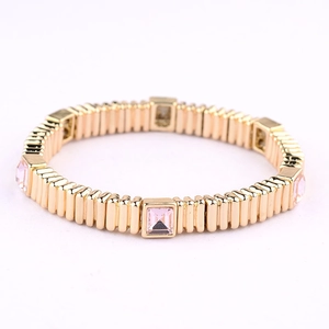 Detailed shot of elastic gold metal bracelet featuring inlaid pink rectangular gemstones