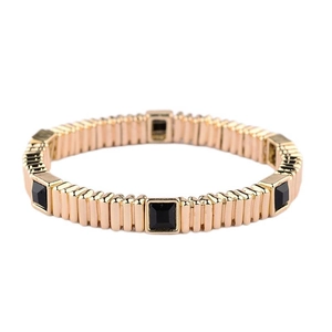 Detailed macro view of gold-tone elastic bracelet featuring black square gemstones