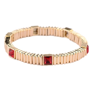 Macro detail of golden metal cube bracelet with square cut red crystals on white background