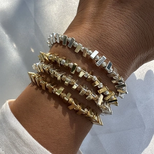 Détail de bracelets élastiques superposés avec texture spirale en or et argent mélangés