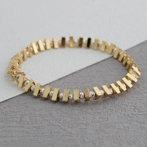 Vue macro des perles géométriques or et argent sur un bracelet extensible au fini poli