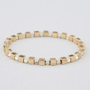 Detailed macro view of geometric square gold beads and faceted silver spacers on the bracelet