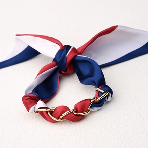 Primer plano de pulsera de seda roja blanca y azul con cadena de metal dorado entrelazada