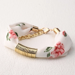 Detalle de pulsera de pañuelo de seda con estampado floral rosa y cadena dorada ajustable