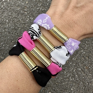 Conjunto de pulseras de tela con estampado paisley y anillos dorados en la muñeca