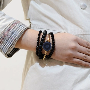 Bracelet doré bohème avec pierre naturelle bleue et perles noires porté au poignet