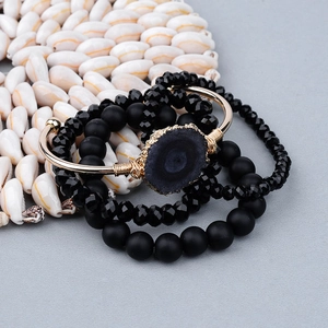 Détail d'un bracelet doré bohème et de bracelets en perles de pierre naturelle noire