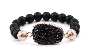 Détail de perles noires mates et pierre druzy avec bordure en or rose sur le bracelet