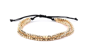 Détail du bracelet double couche en perles dorées avec cordon noir tressé réglable