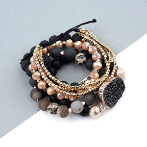 Détail de bracelets bohèmes à plusieurs rangs avec pierres mates et breloque druzy noire