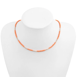 Détail d'un collier de perles orange vif avec touches dorées porté sur un buste blanc